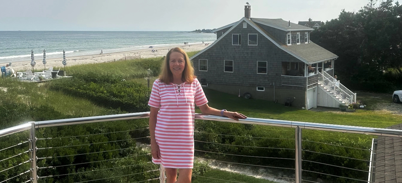 JoAnne, a person living with obstructive sleep apnea, standing in front of a house at the beach