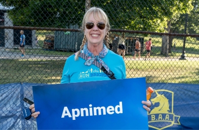 An Apnimed employee holding a sign for a 10K