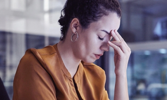 A woman with her eyes closed and her hand on her forehead