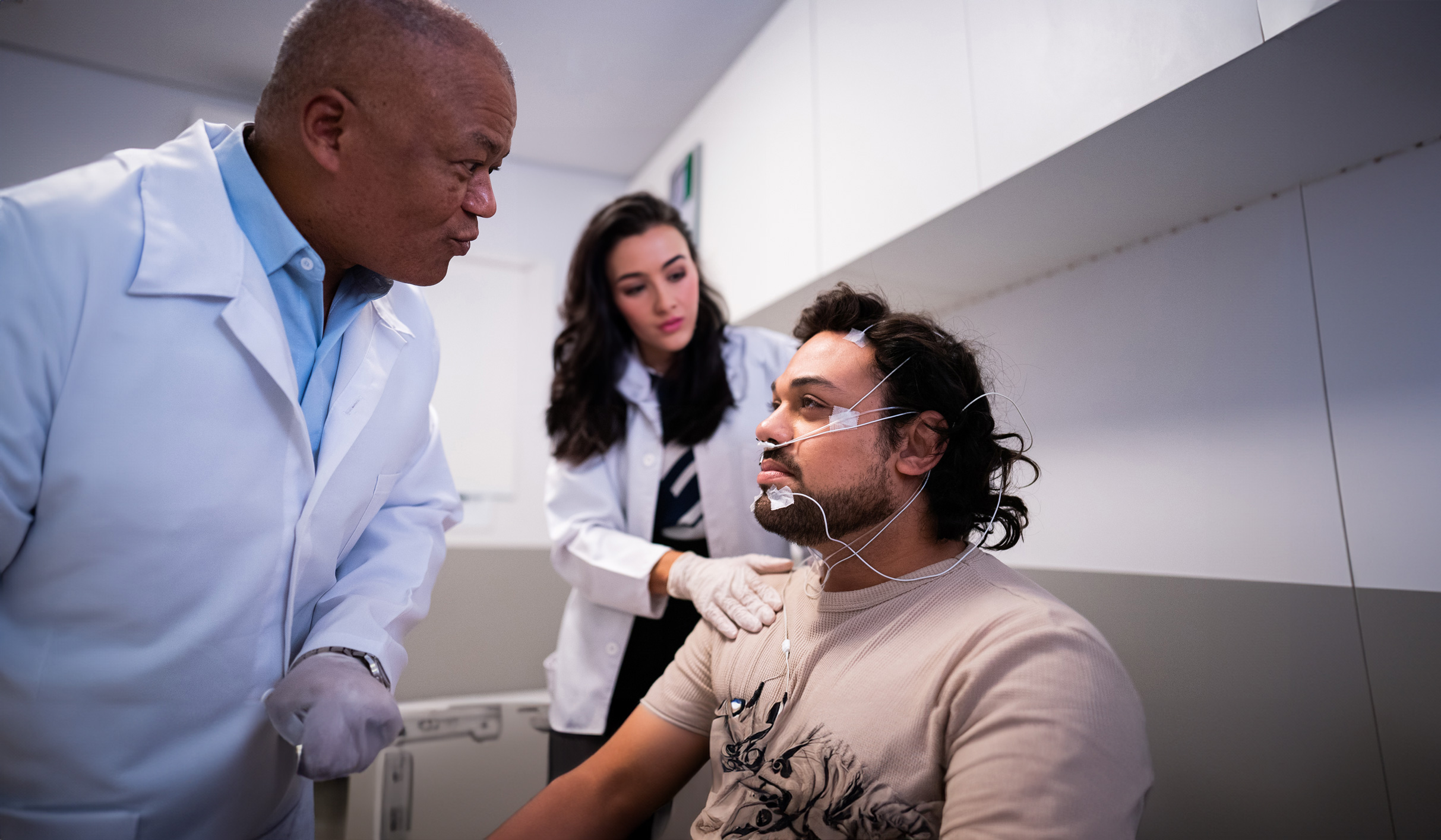 Two doctors examining a patient with surface electrodes on