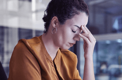 A woman with her eyes closed and her hand on her forehead